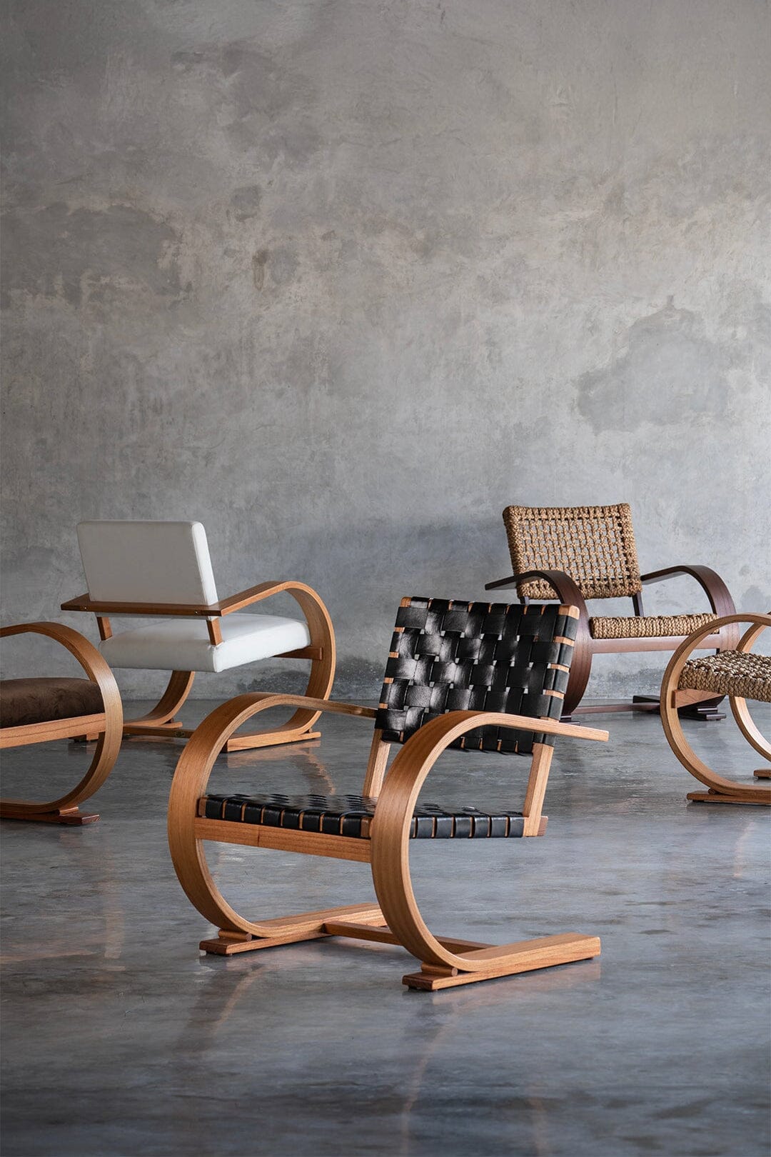 Modern chairs with different designs against a gray concrete wall.