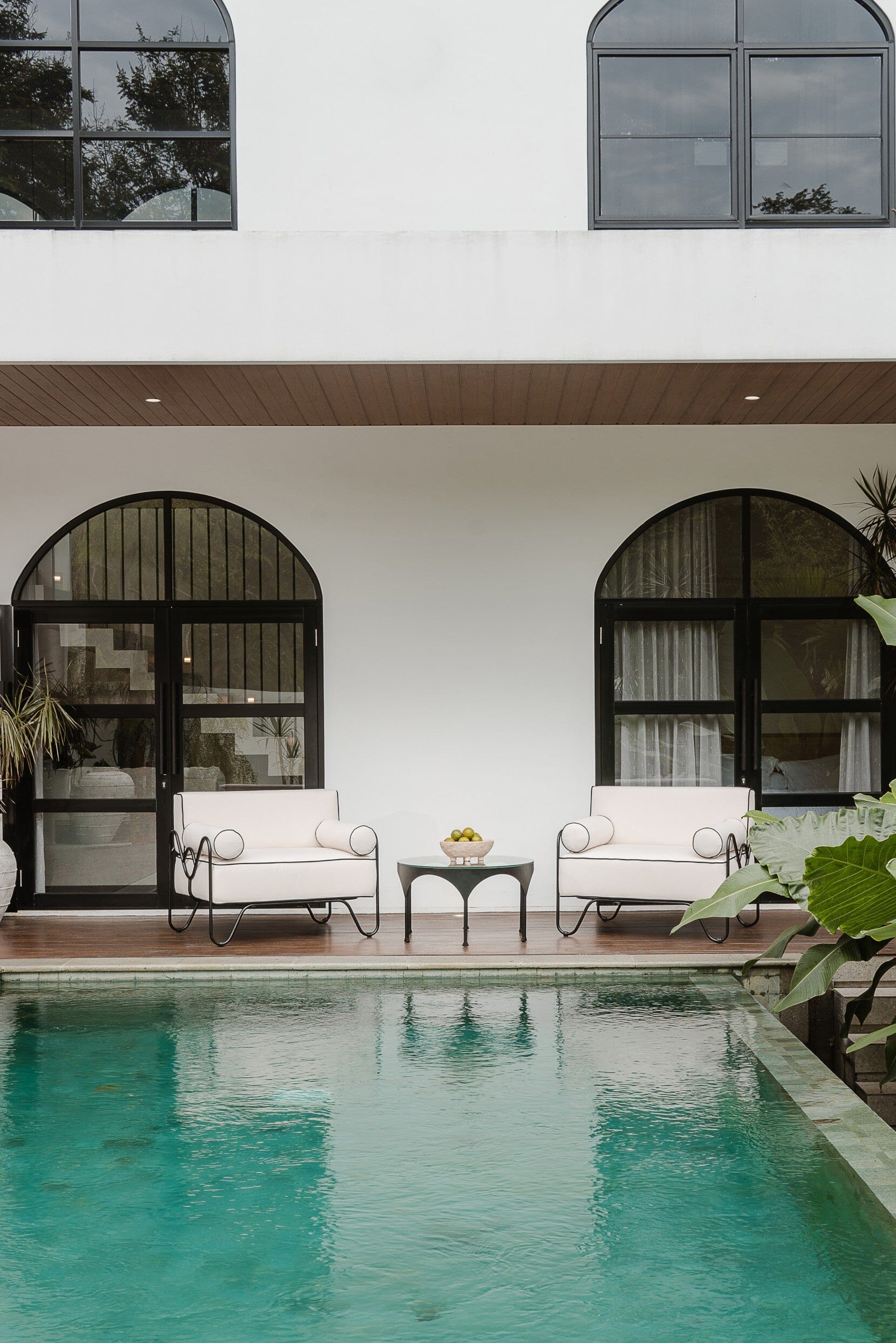 Two white armchairs with outdoor black metal coffee table between