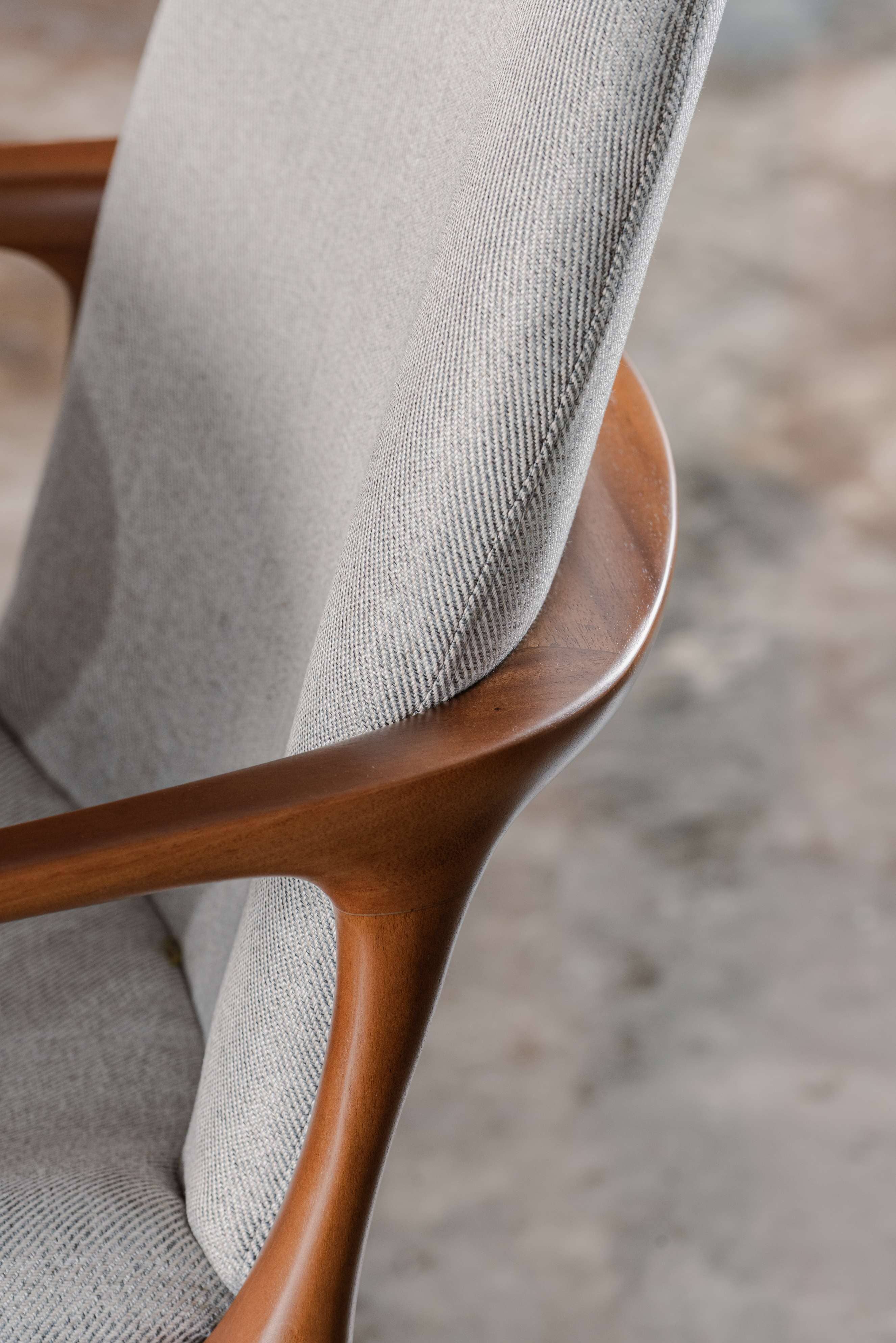 Close-up of a chair with wooden armrests and grey cushion