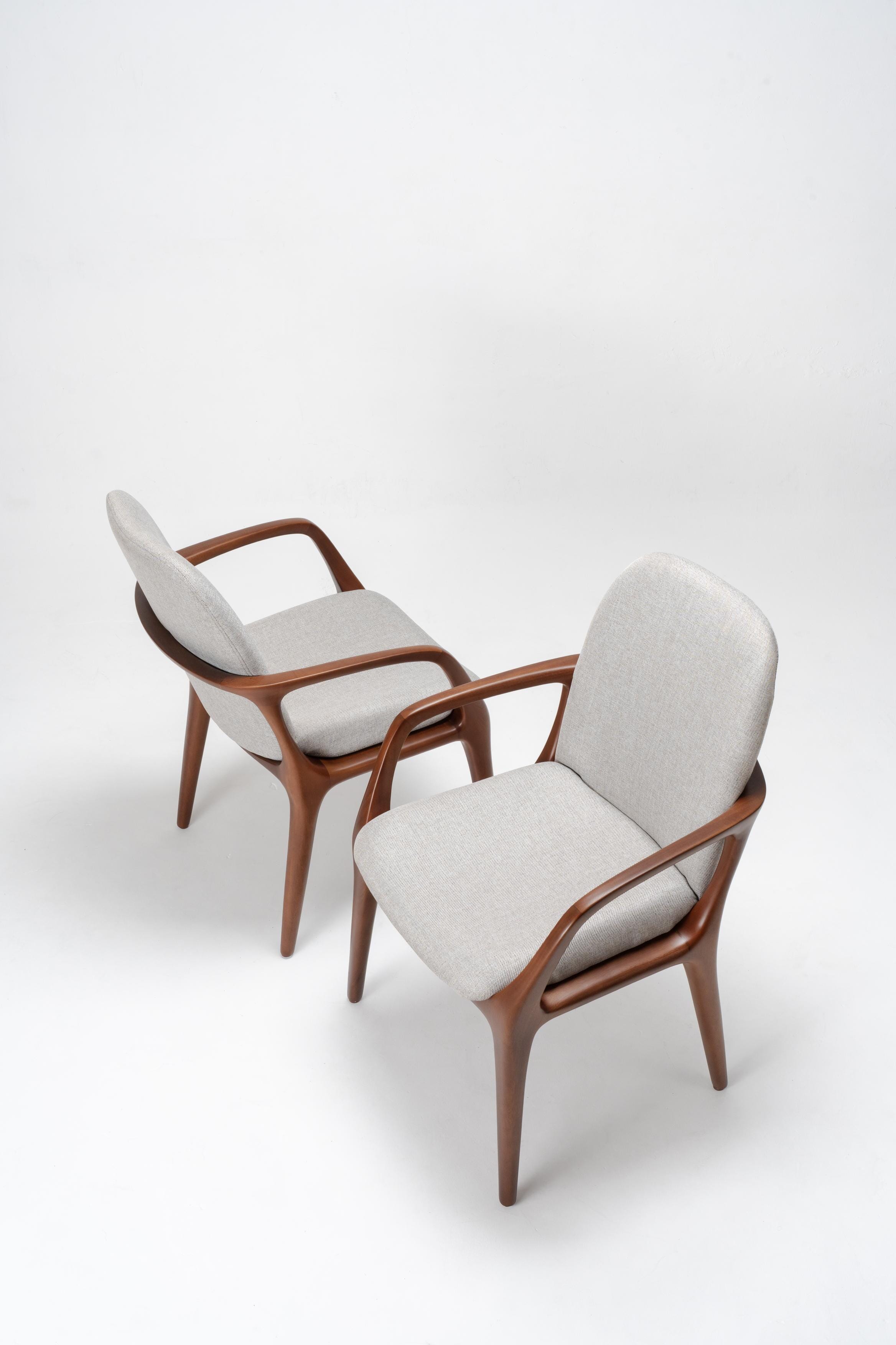 Two dining room chairs with wooden frames and grey cushions