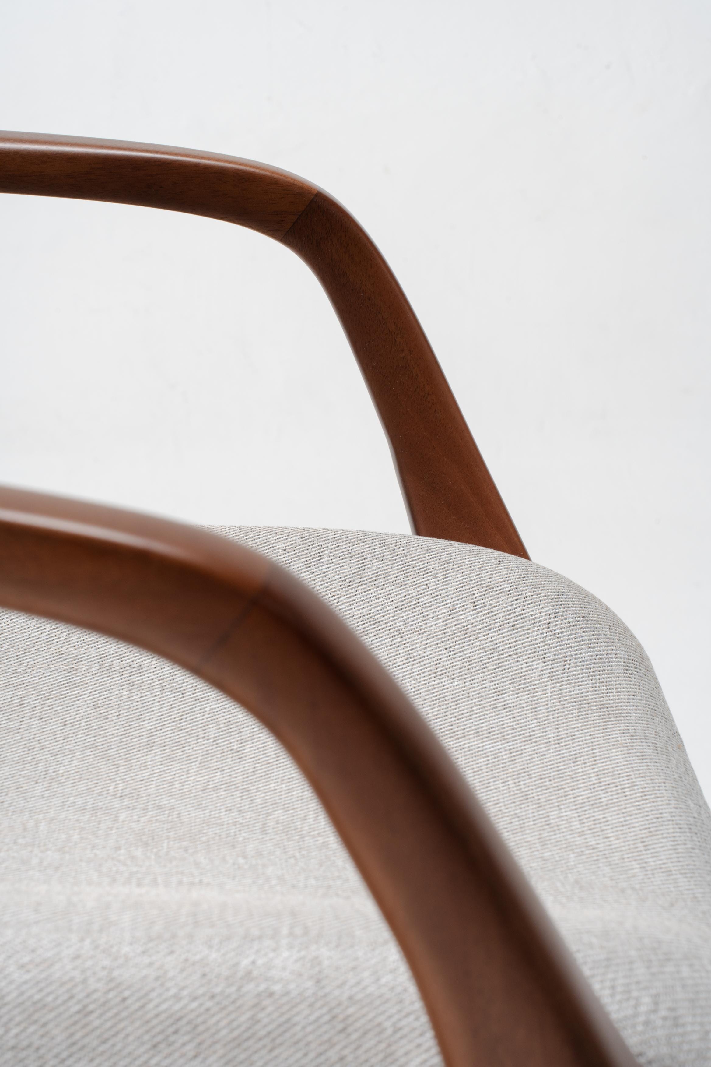 Close-up of a chair with wooden armrests and grey cushioned seat