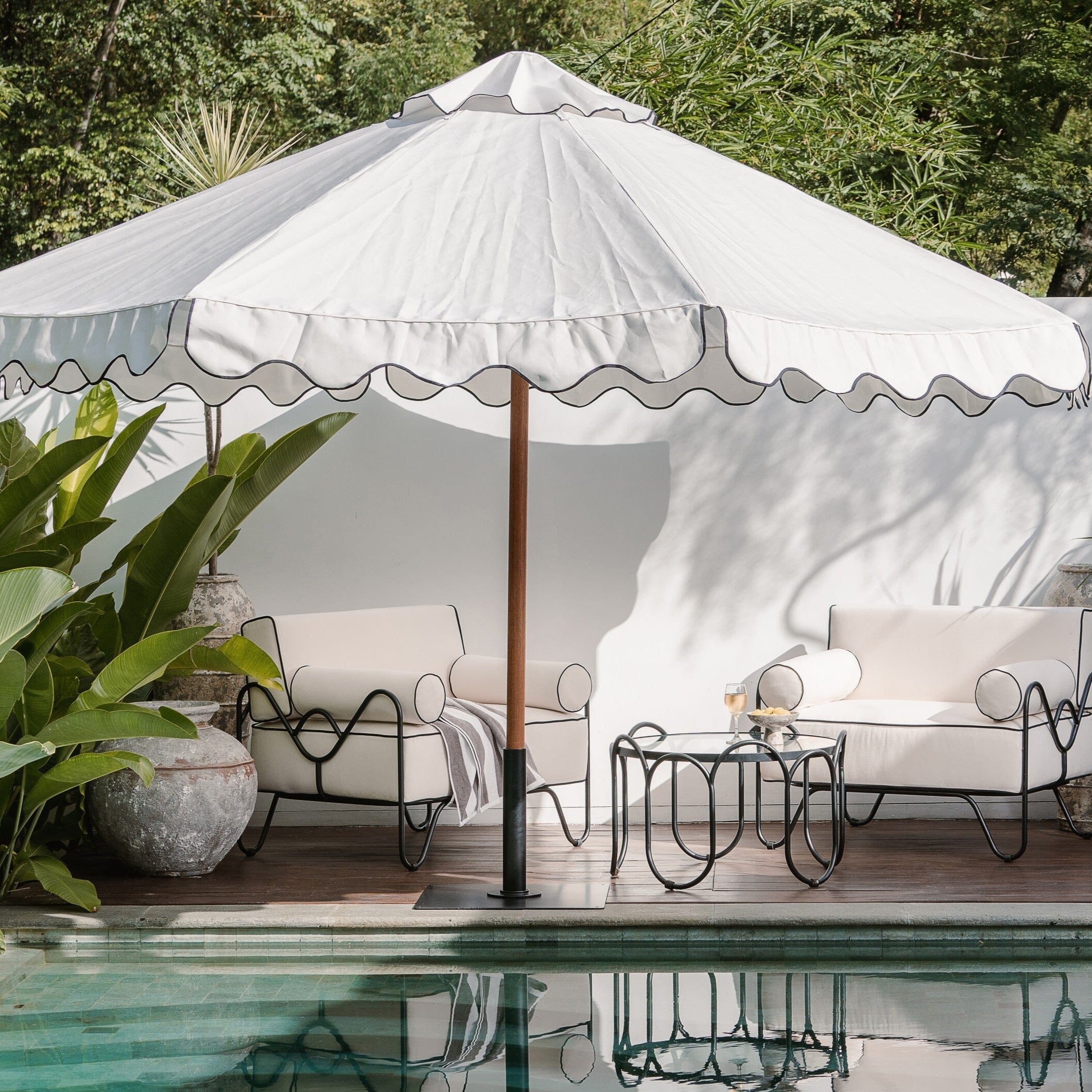 Outdoor patio with white furniture, umbrella, and poolside decor