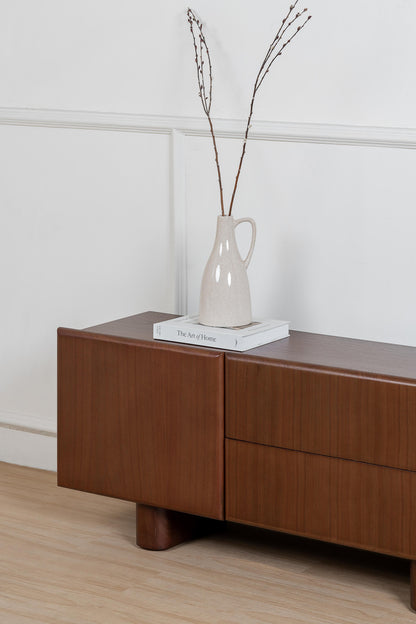 Wooden sideboard with a vase and books on a white wall background