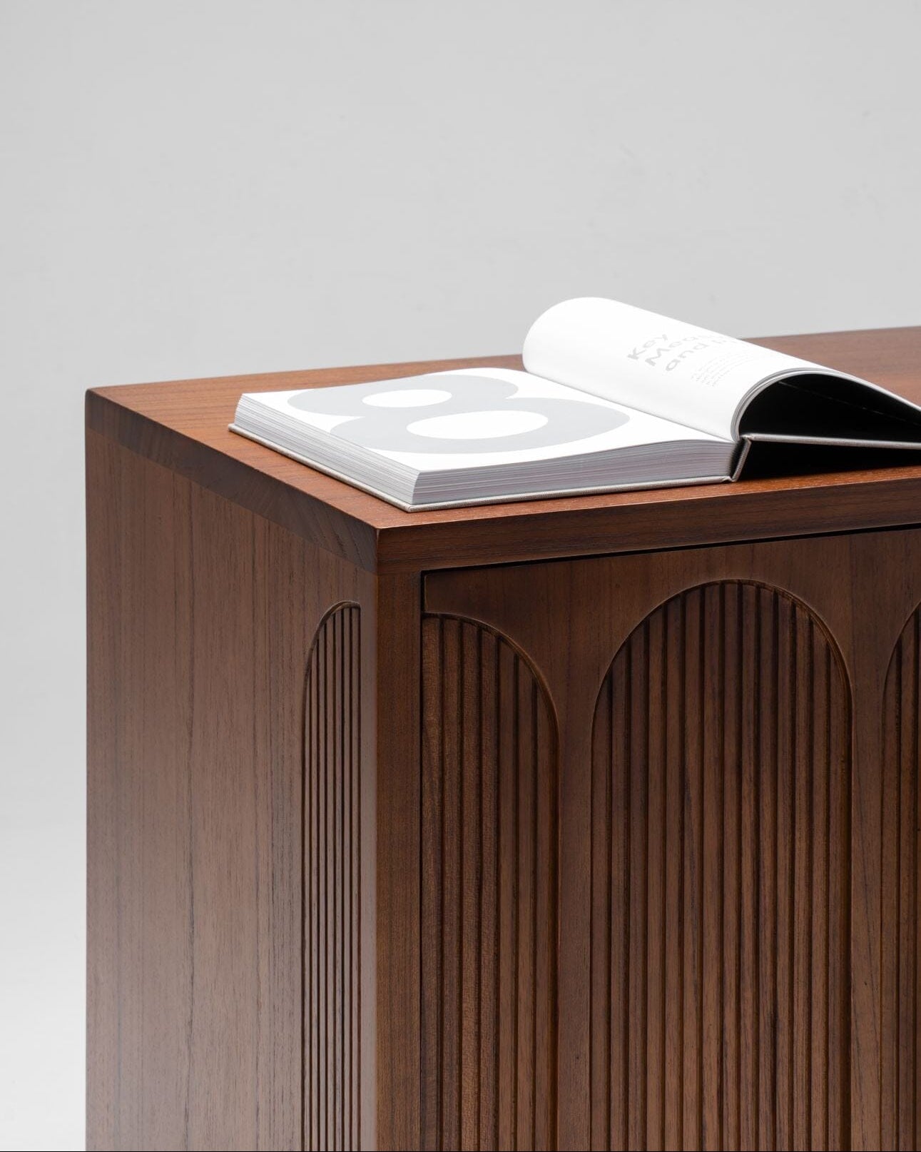 Wooden side table with an open book on a light gray background