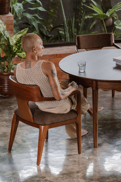 dining chair with arm, upholstered back and seat, in front of round dining table