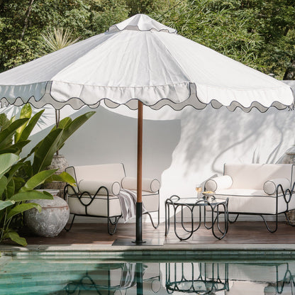 Outdoor patio with white furniture, umbrella, and poolside decor